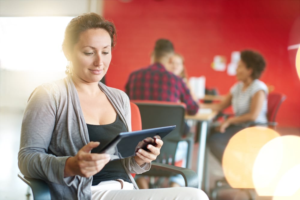 Confident female designer working on a digital tablet in red creative office space-1