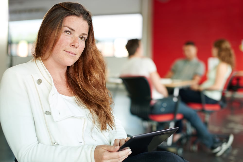 Confident female designer working on a digital tablet in red creative office space